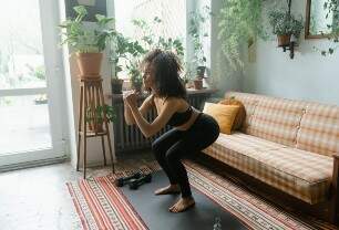Mulher praticando agachamento em uma sala residencial