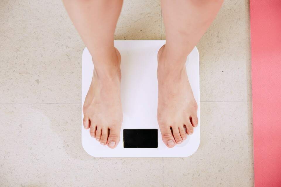 Imagem de uma pessoa se pesando em balança