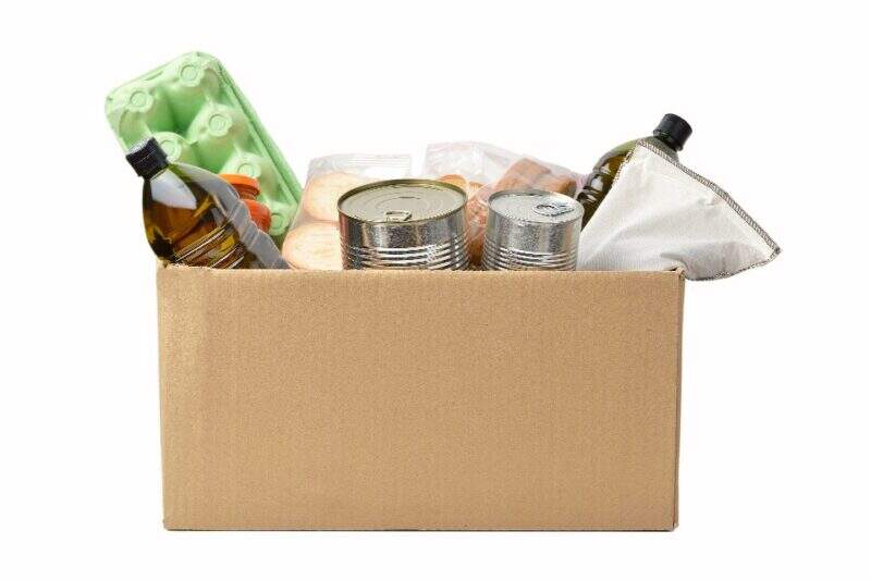 Imagem mostra caixa de papelão cheia de itens alimentares, em sua maioria não-pereecíveis, vistos apenas parcialmente