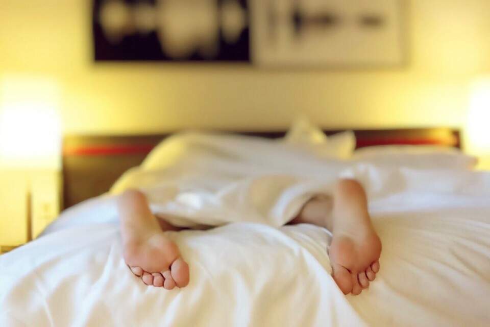 Dois pés aparecendo sob os lençóis