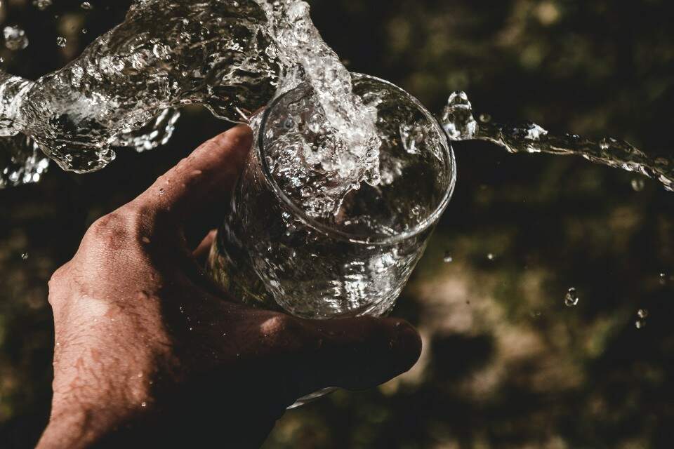 Mão segurando copo d'água