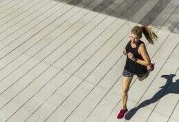 Fotografia aérea mostra mulher em roupas esportivas correndo em área livre