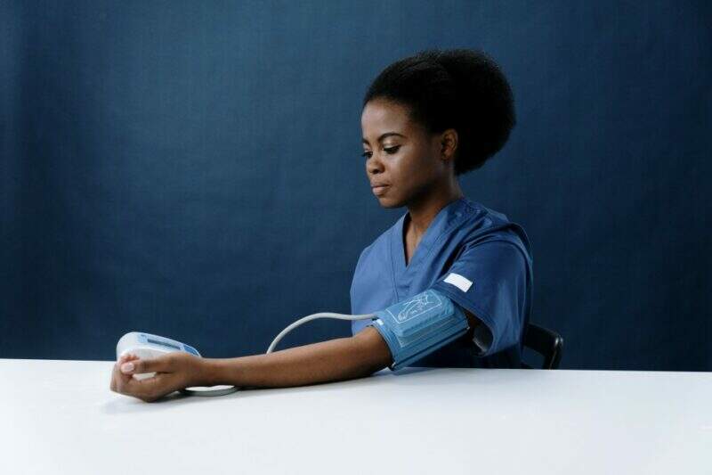 Na imagem, uma mulher mede a própria pressão arterial
