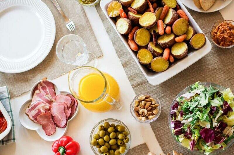 Na imagem, diversos alimentos estão espalhados em uma mesa para simbolizar os nutrientes