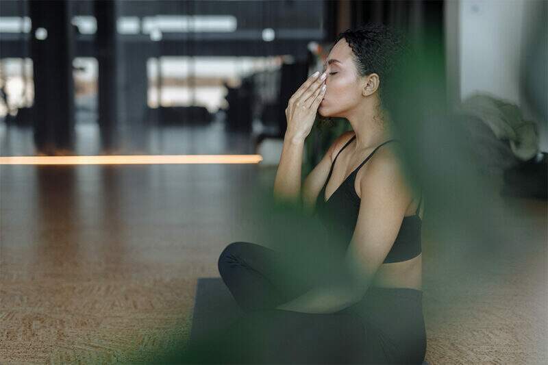 Imagem mostra mulher em posição de meditação, aparentemente praticando exercícios de respiração