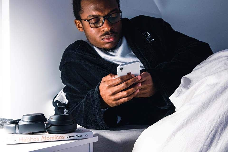 Imagem mostra homem na cama mexendo no celular