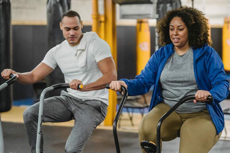 Imagem mostra dupla praticando exercícios em ambiente de academia