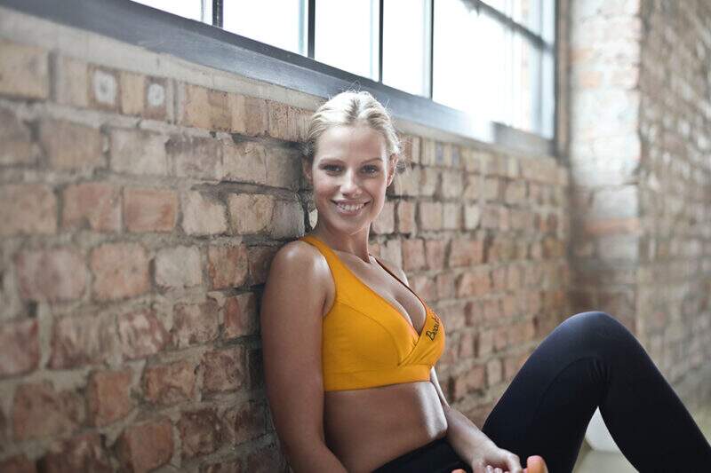 Imagem mostra mulher em roupas de academia sorrindo para a câmera