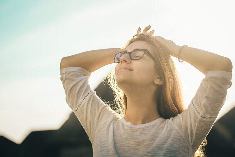 Imagem mostra mulher de óculos tomando sol ao ar livre