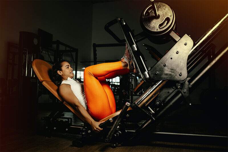 Imagem mostra mulher praticando exercícios no Leg Press