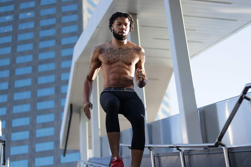 Imagem mostra homem com músculos definidos, sem camisa, descendo um lance de escadas
