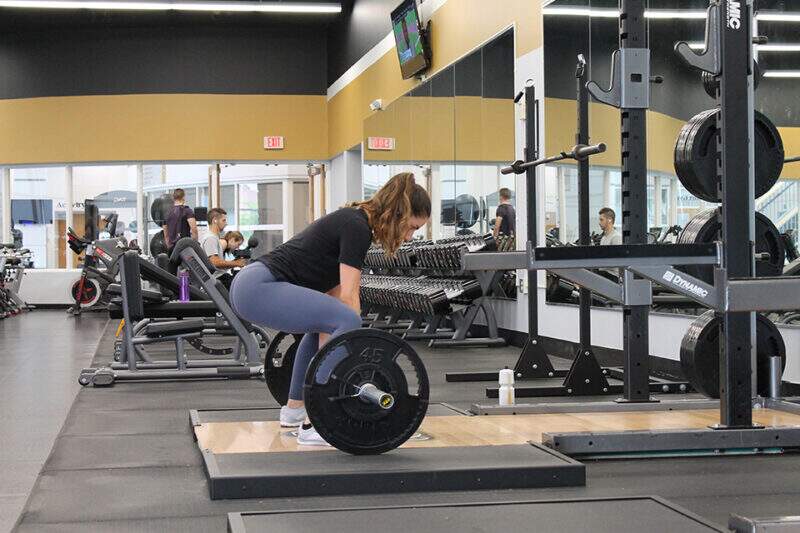 Imagem mostra mulher treinando pela manhã em ambiente de academia