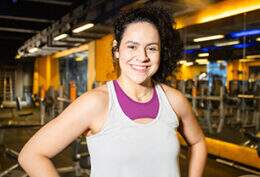 Imagem mostra mulher sorrindo em ambiente de academia