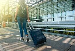 Imagem de pessoa entrando no aeroporto com malas de viagem
