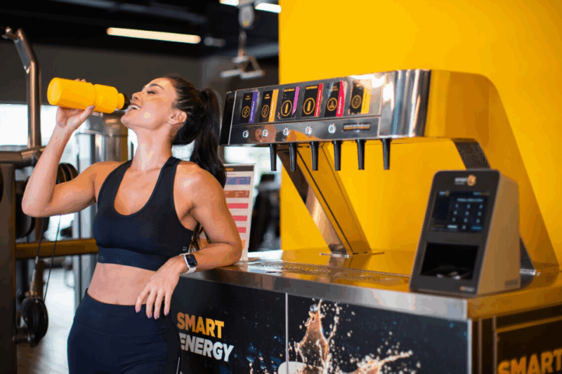Mulher bebendo água em garrafinha da Smart Fit na academia