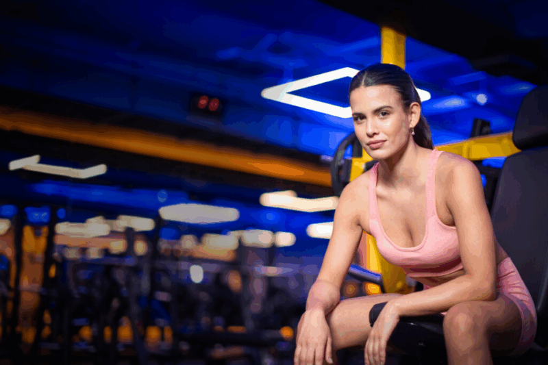 Mulher sentada em banco da academia.