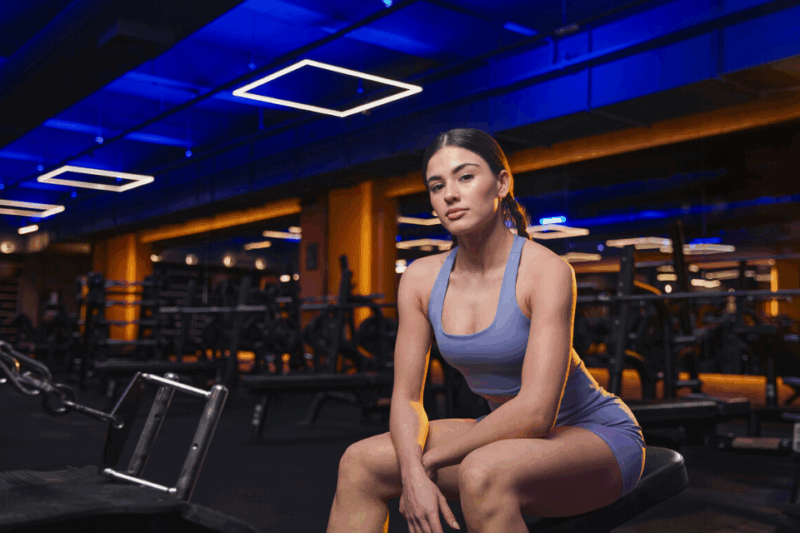 Mulher sentada em banco da academia.