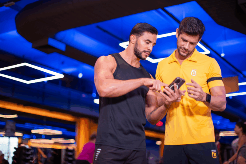 Dois homens olhando no celular o aplicativo da Smart Fit Nutri.