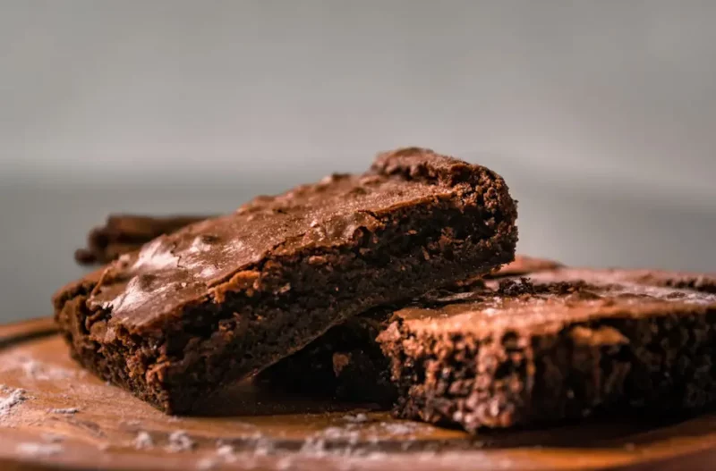 Imagem de dois pedaços de brownie fit sob uma tábua de madeira.