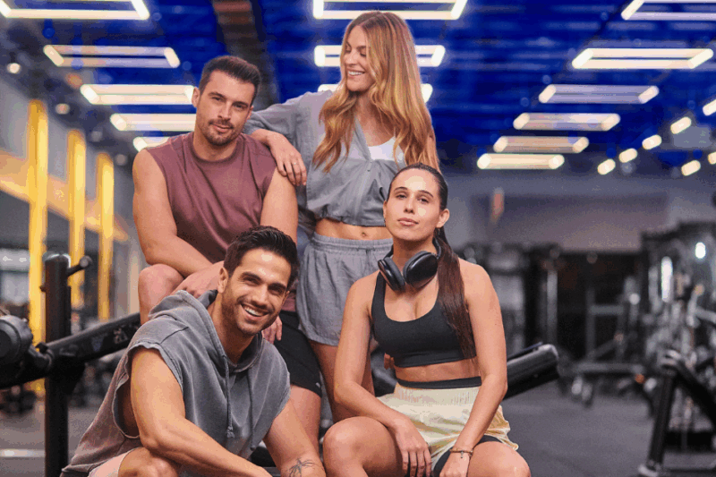 Dois homens e 2 mulheres fazendo pose para tirar foto na academia