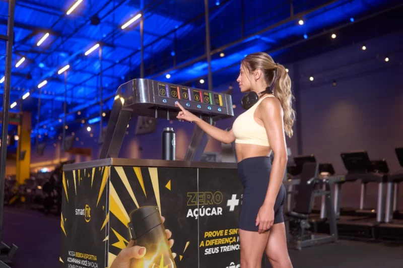 Mulher usando máquina de bebidas fitness na academia