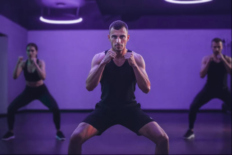 Homem treinando em aula de fitness com luzes roxas