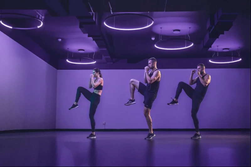 Trio realizando exercícios de boxe em ambiente moderno.