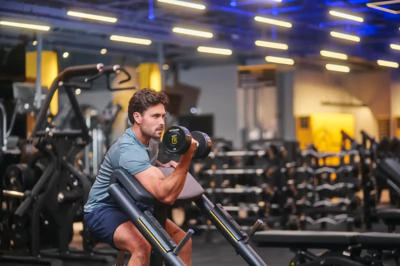 Homem levantando halteres em academia moderna