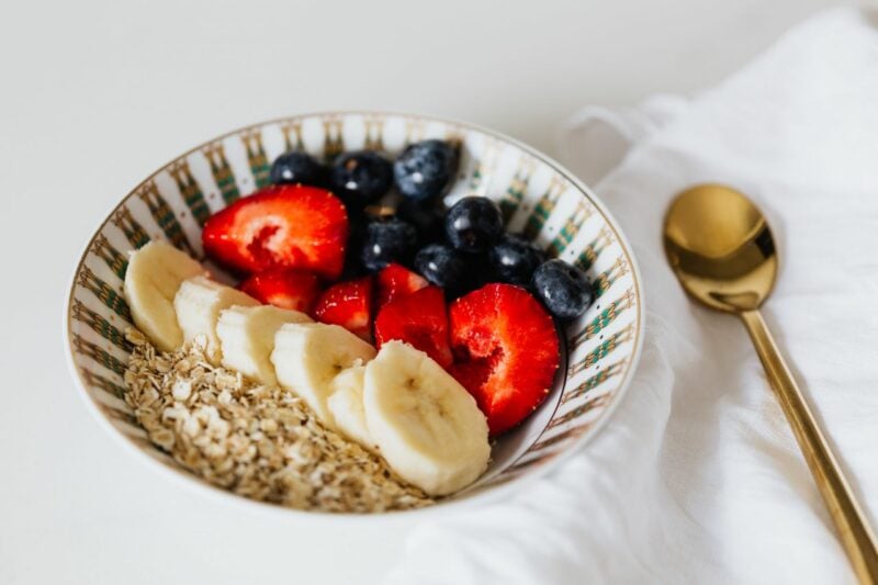 Tigela com frutas, aveia e colher dourada