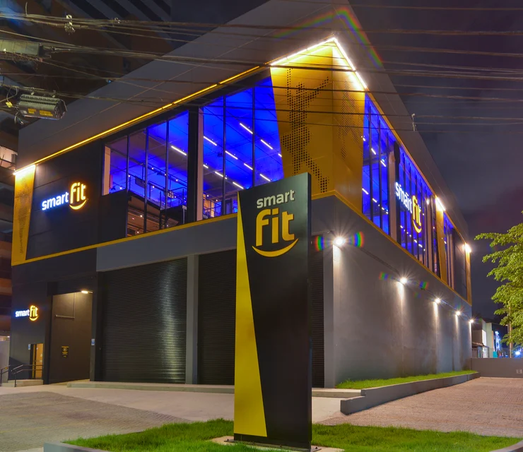 Fachada da academia Smart Fit iluminada à noite
